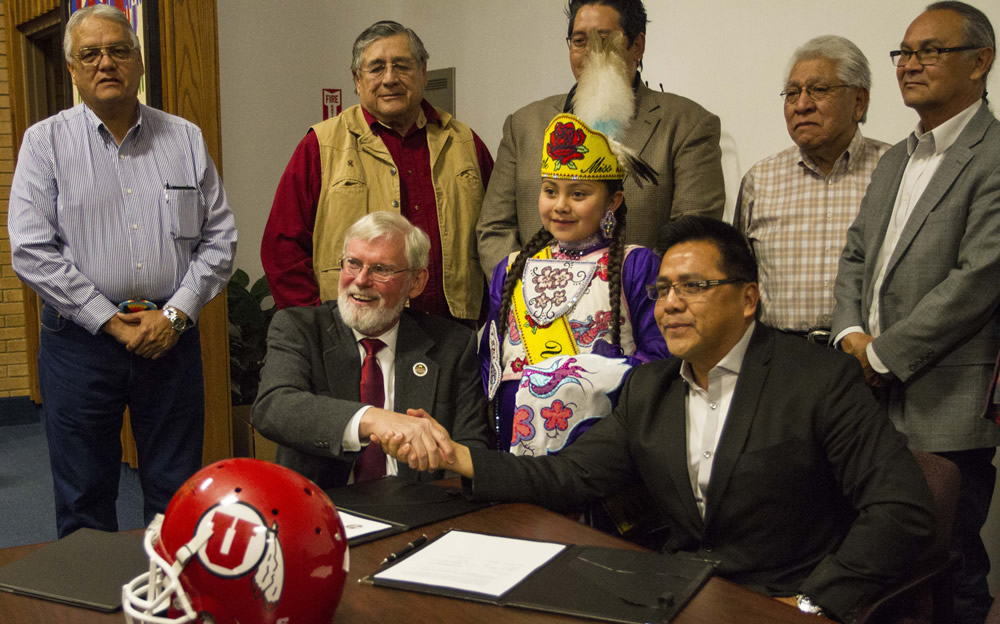 University President David Pershing, seated at left, shakes hands with Gordon Howell, chairman of the Ute Indian Tribe Business Committee.